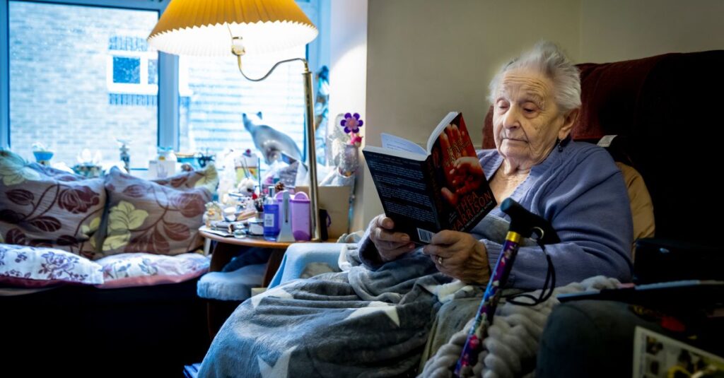 Elderly woman enjoying a book in a cozy living room, embracing retirement leisure time.