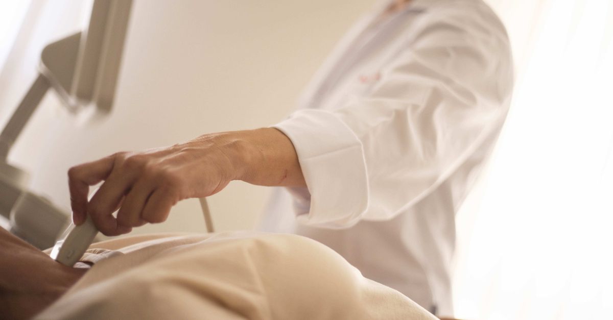 A medical professional conducts an ultrasound on a patient in a clinical setting.
