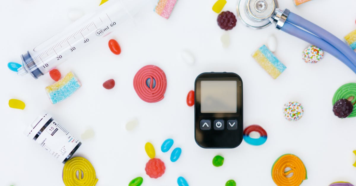 Flat lay of diabetes management tools and colorful candies on white background.
